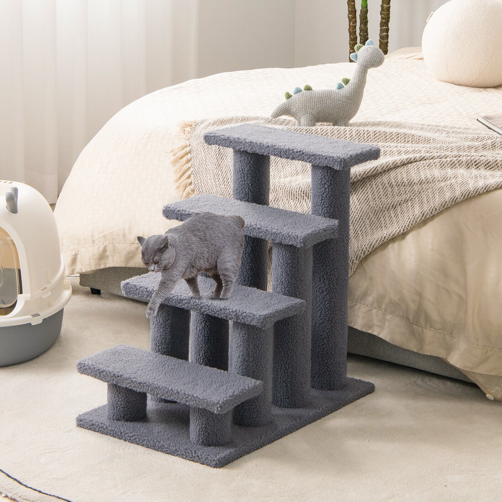 Gray cat tree with a cat climbing on it in a bedroom setting