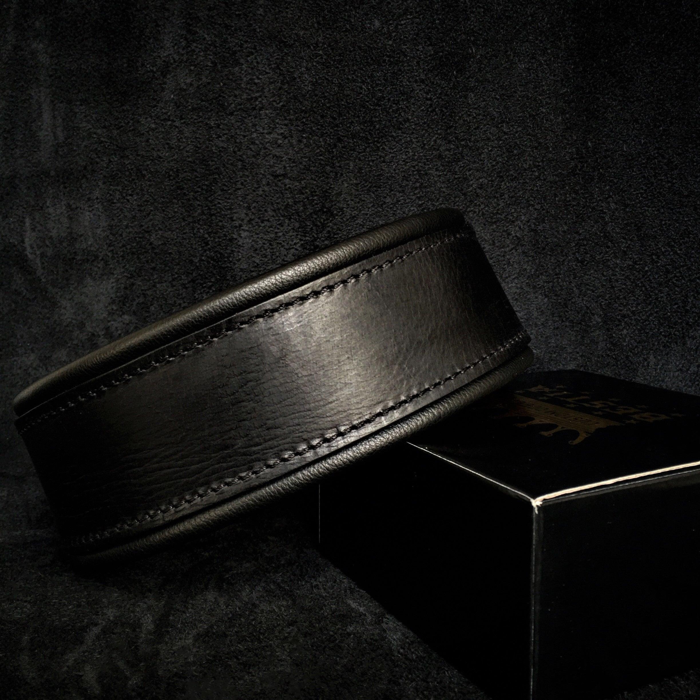 Black leather belt on a dark textured surface